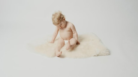 Blonde baby sitting on a rug