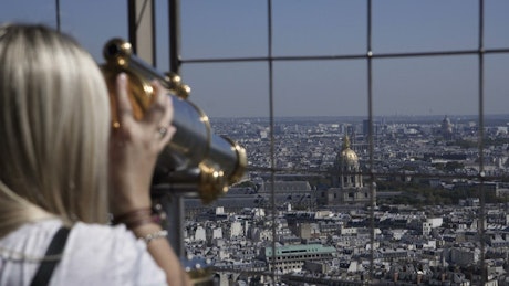 Blonde woman using a telescope in Eiffel tower