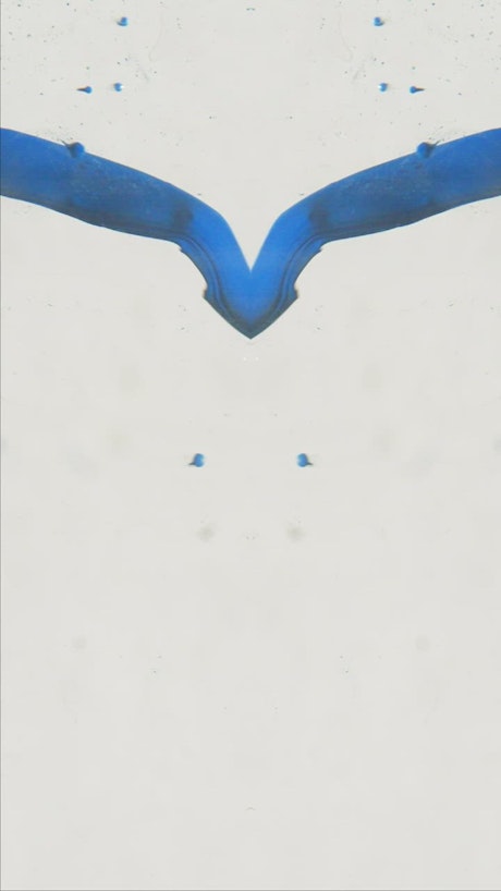Blue ink flowing in water, in a mirrored scene