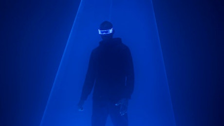 Blue lasers illuminate a man wearing futuristic glasses.