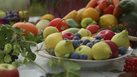 Bowl of fresh pears, blueberries and fruits on a table outside.