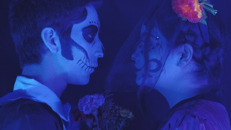 Boy and girl dressed up as Day of the Dead under a blue light