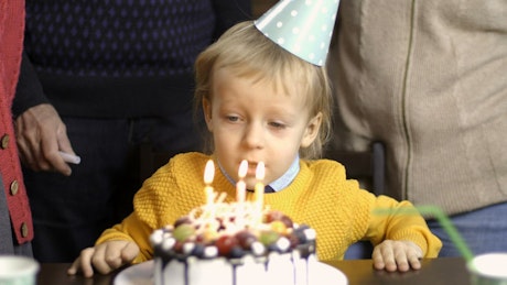 Boy blowing out candles.