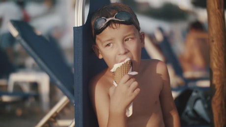 Boy eating an ice cream while looking away.
