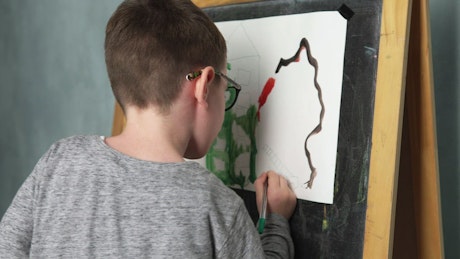 Boy painting a picture with mixed media.