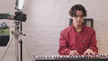 Boy playing piano being recorded.