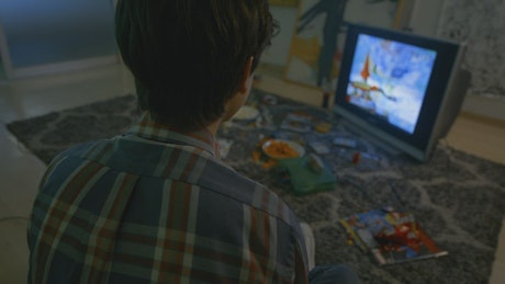 Boy playing video games with chips and candies.