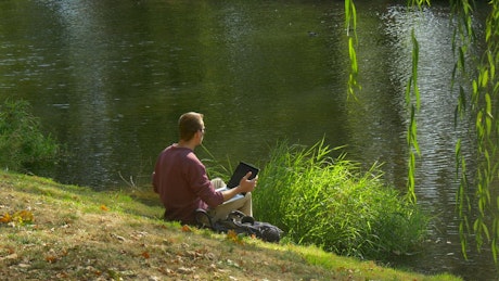 Boy working relaxed on the bank of a river