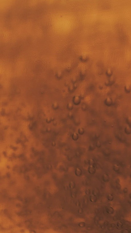 Bubbles moving slowly in a yellow liquid.