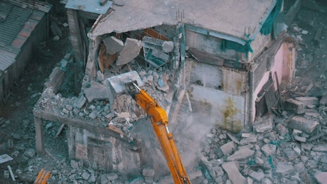 Bulldozer destroying a building in ruins.
