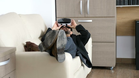 Businessman enjoys VR innovation on sofa in office