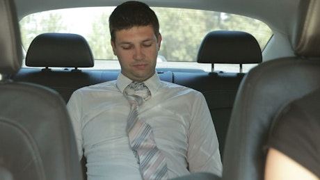 Businessman falling asleep in a car.