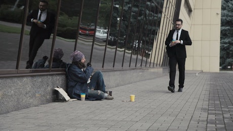 Businessman kicking the beggar's coins.