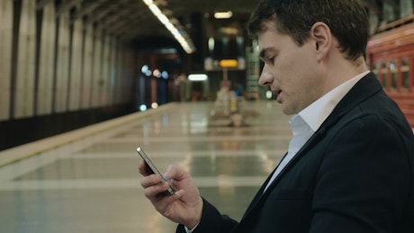 Businessman texting while waiting in the Subway.