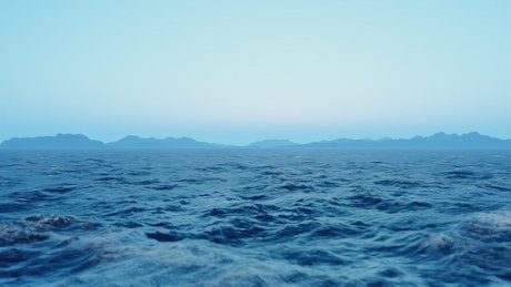 Calm sea waving with mountains in the background