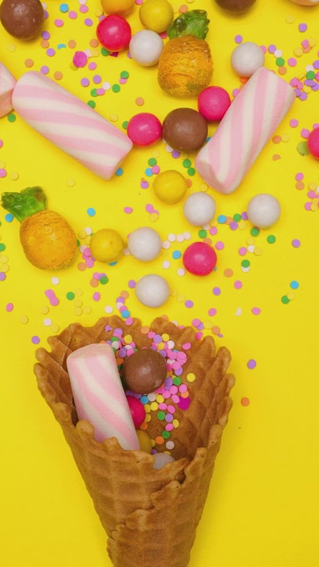 Candies in a waffle cone on a yellow background.