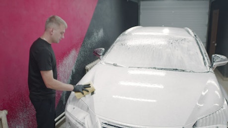 Car covered in soap being washed down in the carwash.