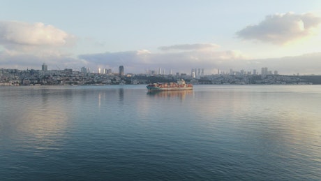 Cargo ship sailing near the coast of a city.