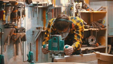 Carpenter sanding wood in his workshop.