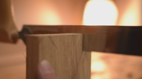 Carpenter sawing a piece of wood, close up
