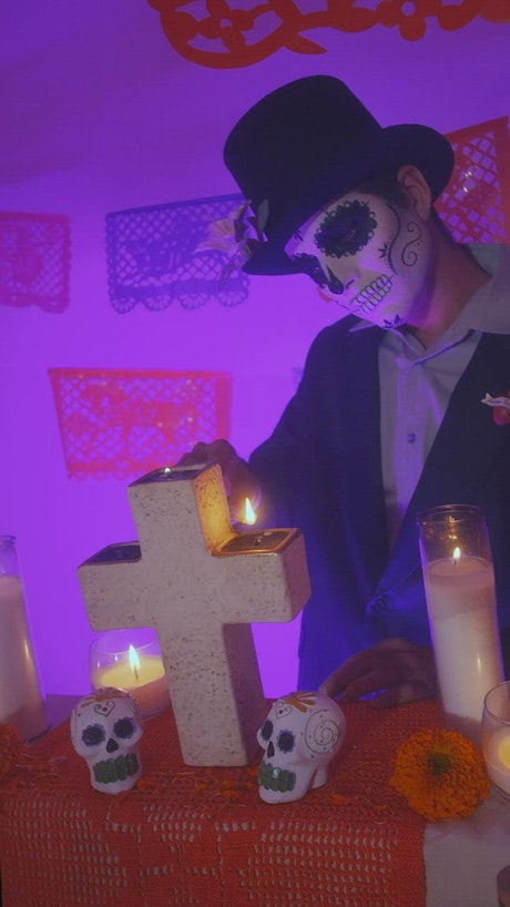 Catrin lighting the candles of an altar of the day of the dead.