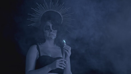 Catrina in the dark with a candle and smoke in Dia de Muertos.