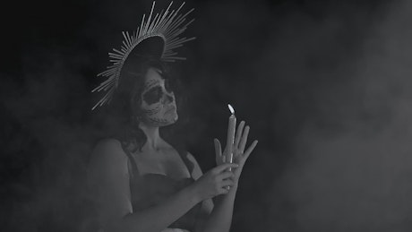 Catrina with a candle, with mist in the dark.