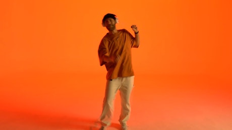 Cheerful dancing of a young man on an orange background.
