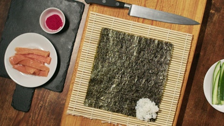 Chef assembling a roll of fresh sushi.