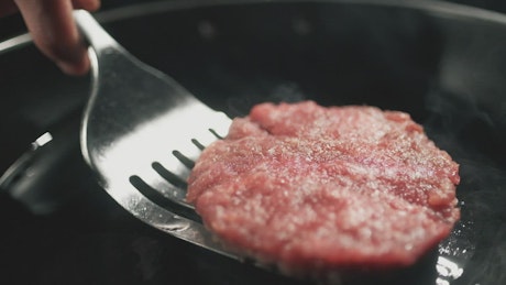 Chef cooking a piece of a hamburger meat.