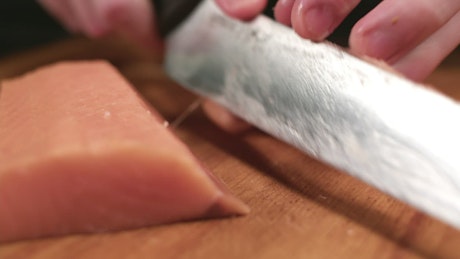 Chef expertly slicing a fresh salmon fillet.
