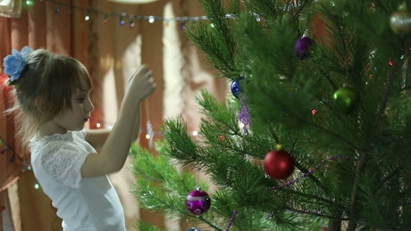 Child decorating a Christmas tree with a snowflake.