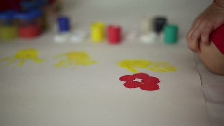 Child paints flowers on butchers paper.