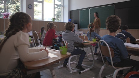 Children in a classroom raising their hands.