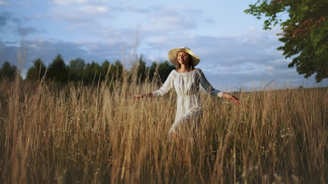 Cinematic of woman walking in field at sunset