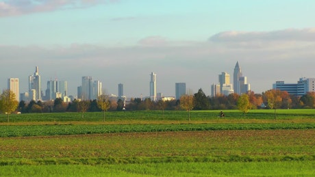 City buildings seen from fields in the countryside.