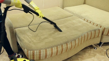 Cleaning dirty furniture with a steam vacuum cleaner.