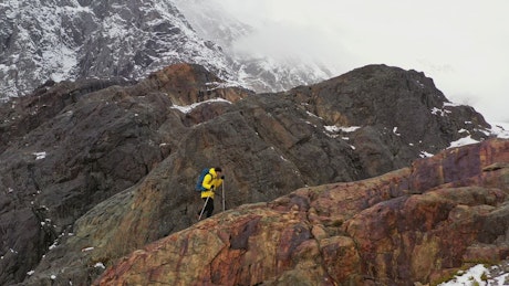 Climber with poles hikes on mountain ridge