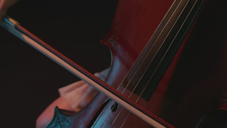 Close shot of a woman playing the cello in the dark.