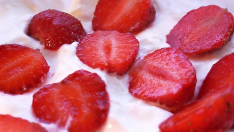 Close up of a bowl of cream covered in juicy strawberries.