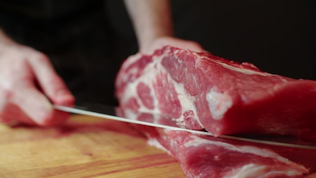 一位厨师熟练地雕刻一大块牛肉的特写镜头