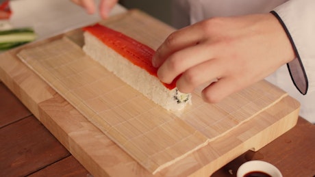 Close up of a chef preparing a traditional sushi roll.