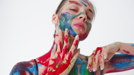 Close up of a dancer covered in paint against a white background.