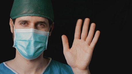 Close up of a doctor waving hello to camera.