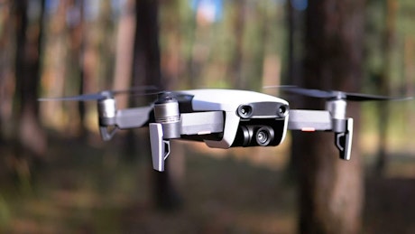 Close up of a drone hovering in the woods.