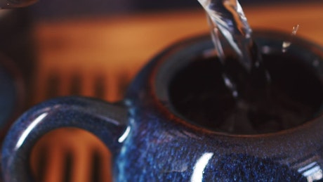 Close up of a expertly crafted teapot being overfilled with water.