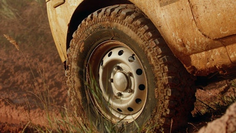 Close up of a four-wheel drive going off road through the mud.