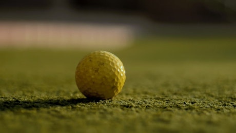 Close up of a golf club putting a golf ball.