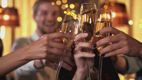 Close up of a group of friends sharing a toast at a party.
