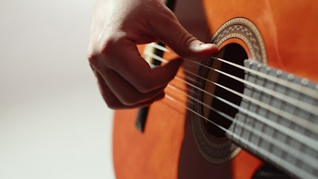 Close up of a guitarist lightly strumming a guitar.